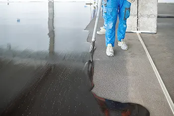A contractor pouring liquid waterproofing membrane in a commercial building - 350