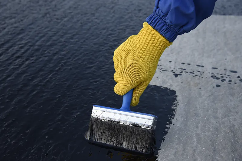 A contractor applying a waterproof coating to the inside of a basement to waterproof it in Long Island.