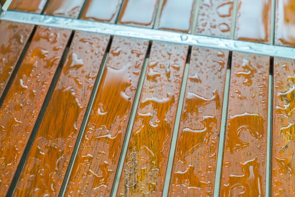 A wooden deck with standing water because of the rain