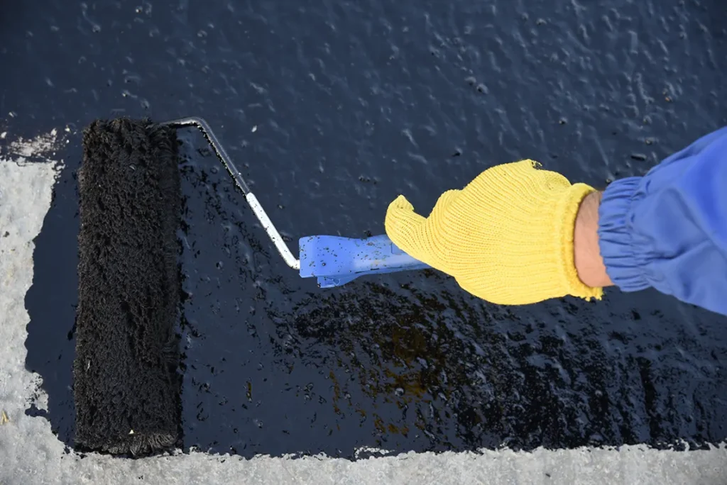 A contractor applying a waterproof coating on a roof