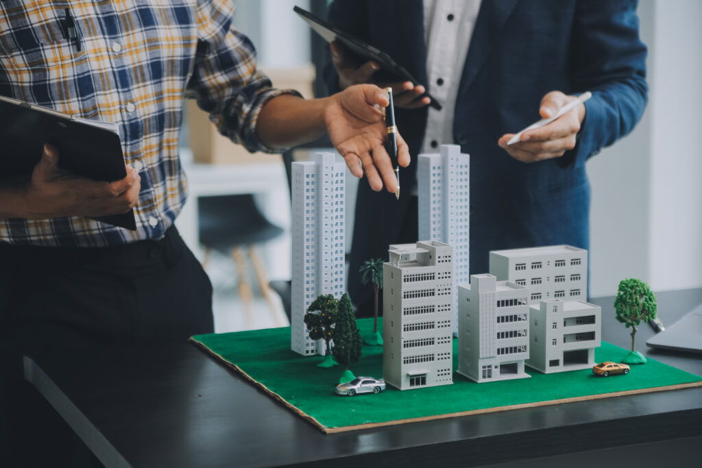 A contractor head discussing drainage system layout with a commercial project manager over the model of the entire building.
